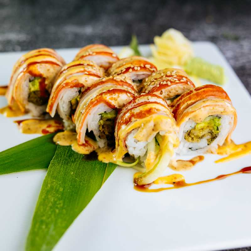 A close-up of a colorful sushi roll with sauces drizzled on top, representing the delectable offerings at sushi restaurants like Sushi King Westside, Coors Boulevard Northwest, Albuquerque, NM.