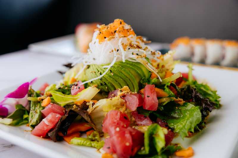 A vibrant sushi salad topped with avocado, tomatoes, and greens, a must-try for anyone searching for sushi near me or Japanese food near me.